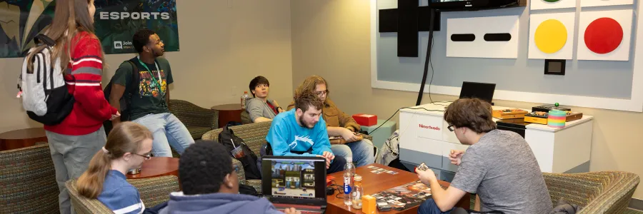 Seven students gathered around game consoles and screen s in Norm's Loft in the student union for e-sports