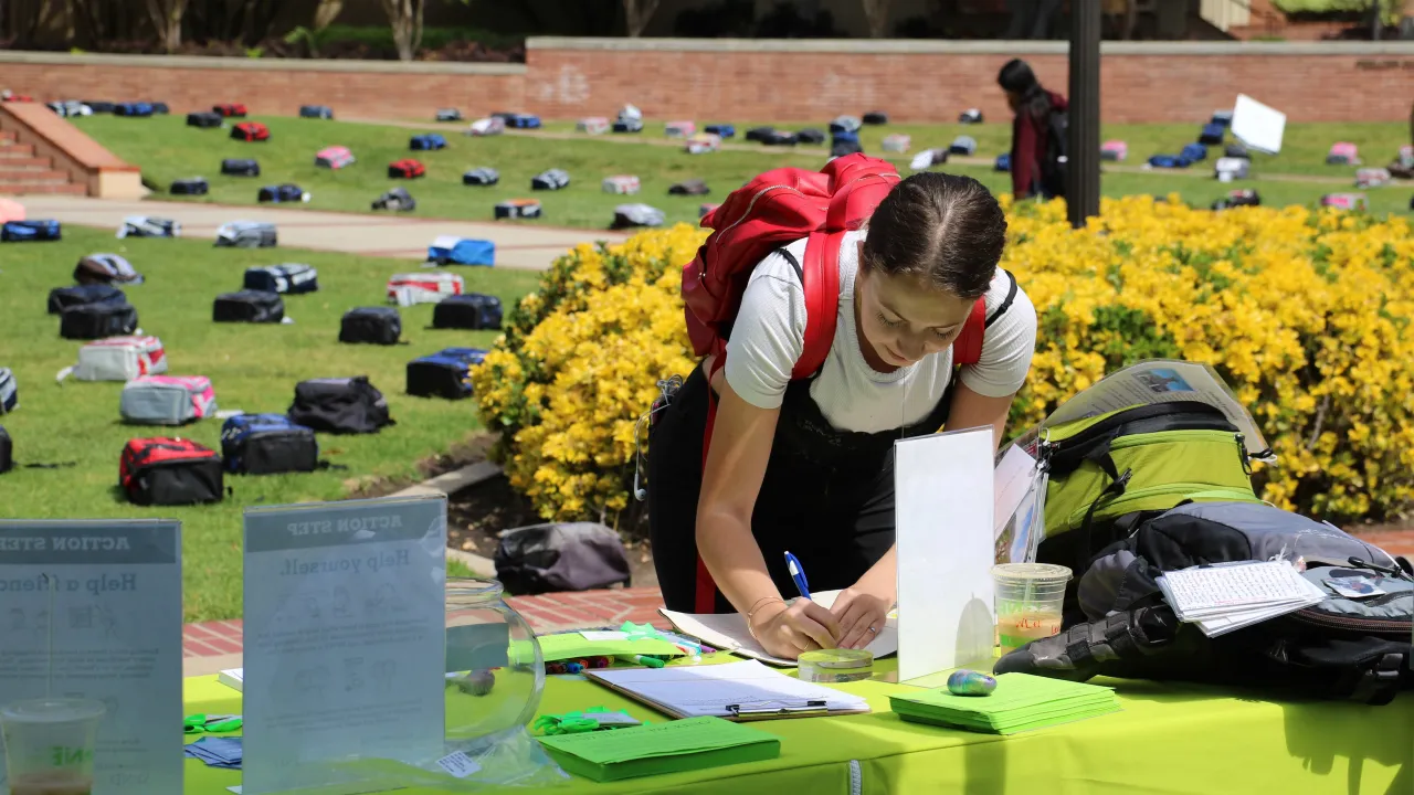 A student writing at a table at the Send Silence Packing event