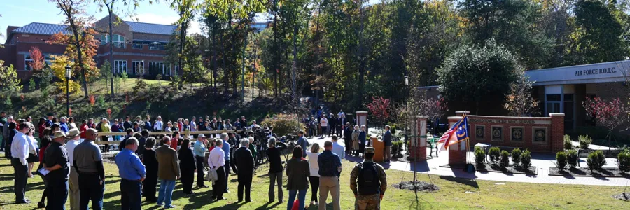 A crowd standing in Veterans Park for a service.